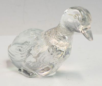 figurine de canard en verre transparent posée sur une surface blanche