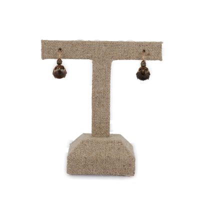 un gros plan sur une paire de boucles d'oreilles posées sur un présentoir, sur fond blanc