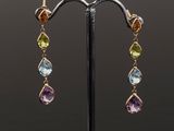 a pair of multicolored earrings on a black stand
