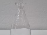 a clear glass bottle with a handle on a white table