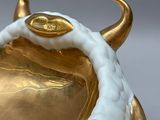 a gold and white vase with a bull head on it