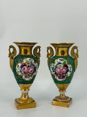 une paire de vases verts et dorés ornés de fleurs, posés sur un fond blanc