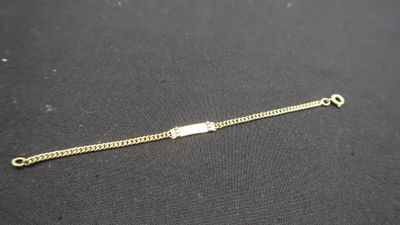 gros plan d'un bracelet en or sur une surface noire