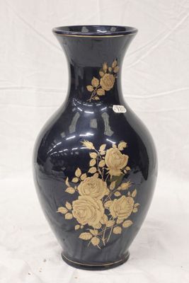 a black vase with gold flowers on it on a white background