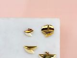 trois boucles d'oreilles en forme de poissons rouges posées sur un bloc de marbre