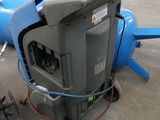a machine that is sitting on the ground next to a blue pipe