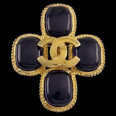 un gros plan sur une broche Chanel noire et dorée