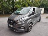 La camionnette grise est garée sur un parking, avec des arbres en arrière-plan.