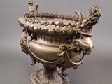 a silver vase with a bird on top of it
