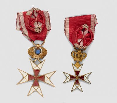 two medals and a cross are on display on a white surface