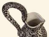 a black and white pitcher with a handle on a table