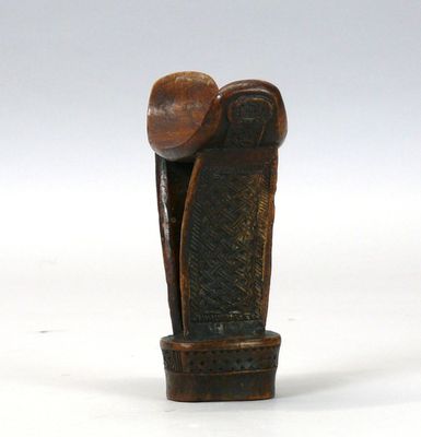 une vieille sculpture en bois représentant un homme coiffé d'un chapeau