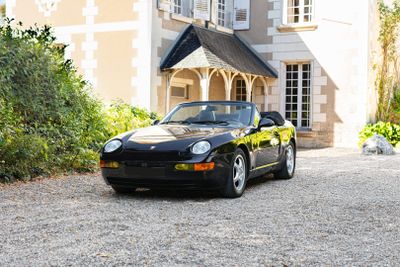 une voiture de sport noire garée devant une grande maison
