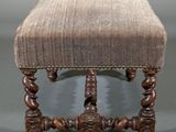 an antique foot stool with a brown upholstered cushion and wooden legs