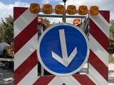 a red and white striped sign with a blue arrow on it