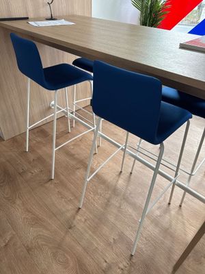 three blue chairs sitting at a table with a red, white, and blue flag on it