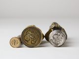 a close up of three wax seals with initials on them