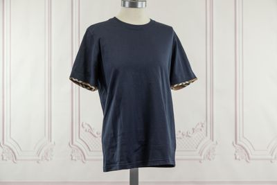 un t-shirt bleu marine sur un mannequin posé devant un mur blanc