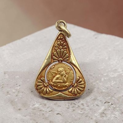 un gros plan d'un pendentif en or posé sur une surface en pierre