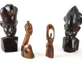 trois figurines en bois de formes et de tailles différentes posées sur une surface blanche