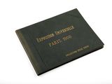 an old black book with gold lettering on it sitting on a white surface