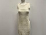 a white dress on a mannequin stand against a white wall