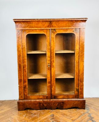 une vieille armoire en bois avec des portes vitrées, posée sur un parquet