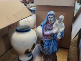 une statue représentant une femme tenant un bébé et un vase posés sur une table