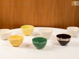 many bowls sitting on a white table with a wooden wall in the background