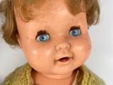a close up of a doll with blue eyes and a sweater on