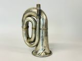 an old silver trumpet sitting on top of a white surface