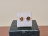 a pair of gold stud earrings sitting on top of a marble block