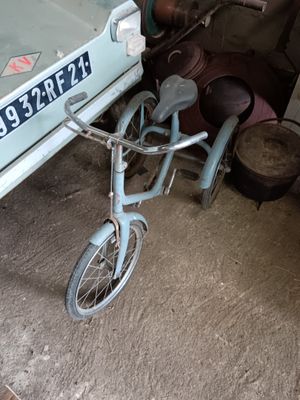 a small child ' s bike that is parked in front of a car