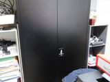 une armoire noire dans un coin d'une pièce où il y a beaucoup de livres