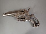 an old silver revolver sitting on top of a white table