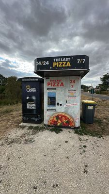 a vending machine with a pizza on it in the middle of the road