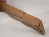 a person holding a piece of wood with a knife in it