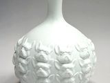 a white vase with flowers on it sitting on a table