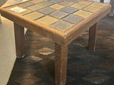 a small wooden table with a tile top on the floor