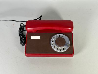 un téléphone rouge posé sur une table blanche, avec un fil
