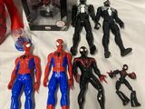 spider - man action figures and other toys are on a bed