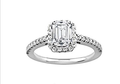 une bague de fiançailles en or blanc sertie d'une émeraude entourée de diamants