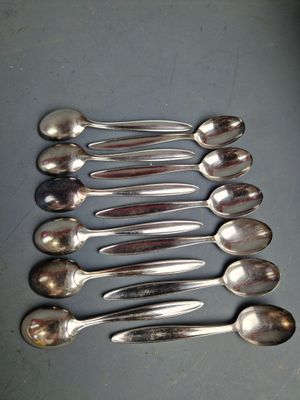 six cuillères en argent sont disposées en rangée sur une table