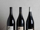 trois bouteilles de vin sont alignées sur une table en bois
