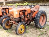 un vieux tracteur qui est à l'abandon dans l'herbe