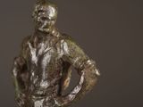 a bronze statue of a man standing with his hands on his hips
