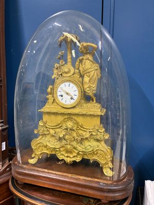 une horloge en or sous un dôme de verre sur une table