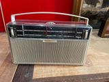 an old radio sitting on top of a wooden table next to a red wall