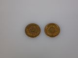 two gold coins sitting side by side on a white surface