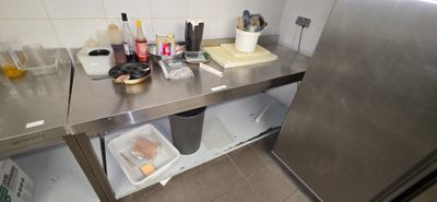 a stainless steel counter top with a trash can and other items